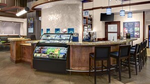 A bar area with a counter, seating, and a display case with snacks.