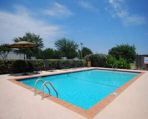 A rectangular swimming pool with a tiled edge, surrounded by a beige deck. There are lounge chairs and a single umbrella. - Super 8 by Wyndham Grapevine/DFW Airport Northwest (Grapevine)