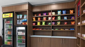 Una máquina expendedora y estantes con productos de comida en una tienda.