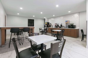 Una cocina moderna con encimeras blancas, sillas negras y una mesa blanca.
