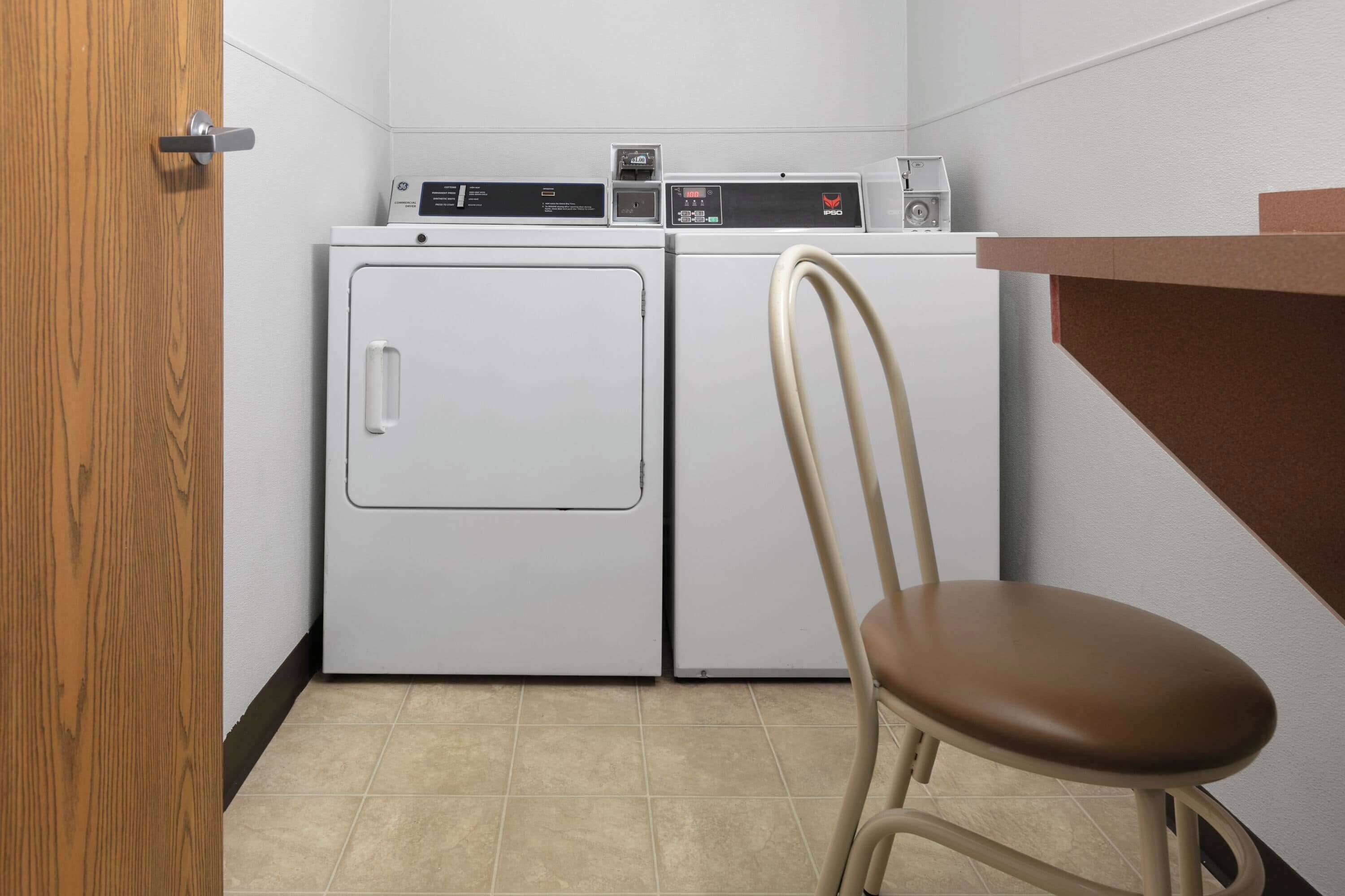 Une buanderie équipée d’un lave-linge, d’un sèche-linge et d’une chaise.