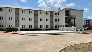 A multi-story building with a flat roof, a central staircase, and a parking area.