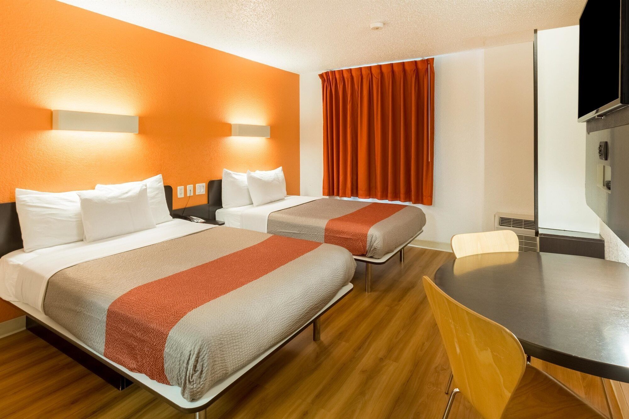 A hotel room with two beds, a dining table, and a TV.