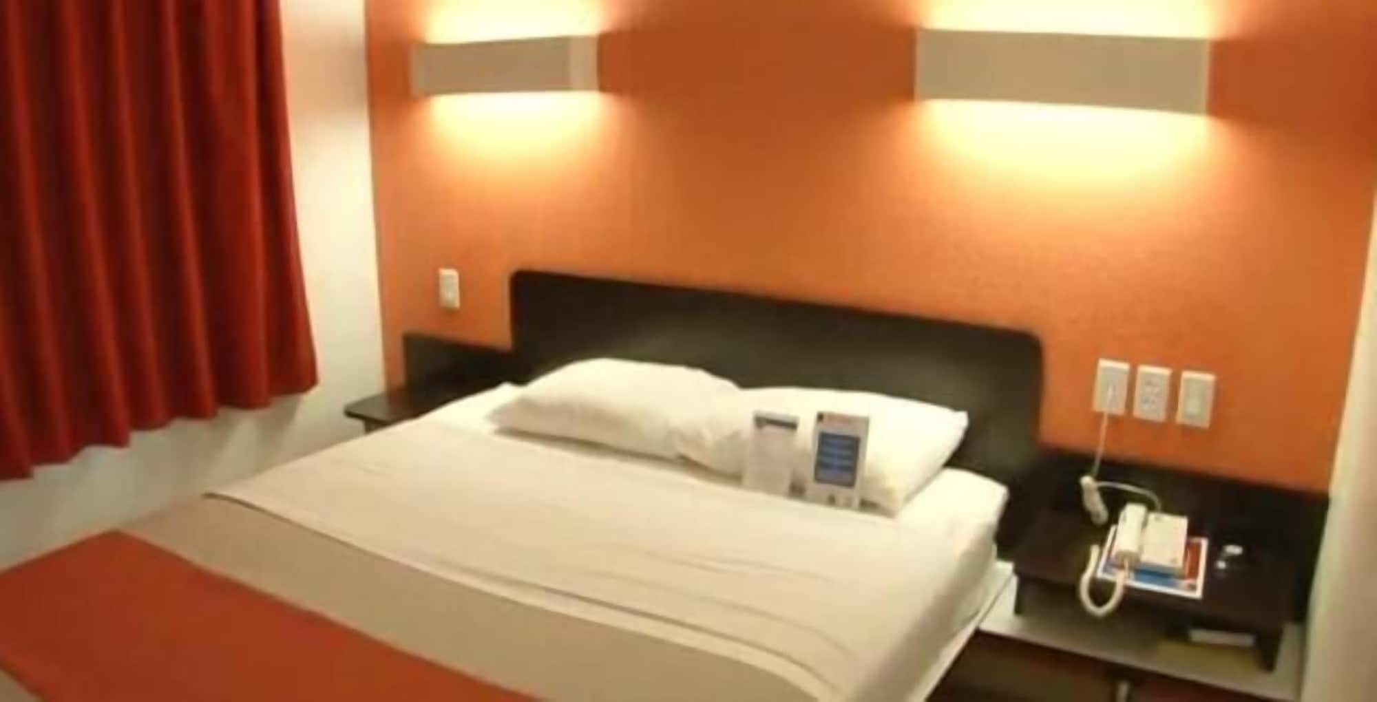 Habitación de hotel con cama, mesita de noche y teléfono en la pared.