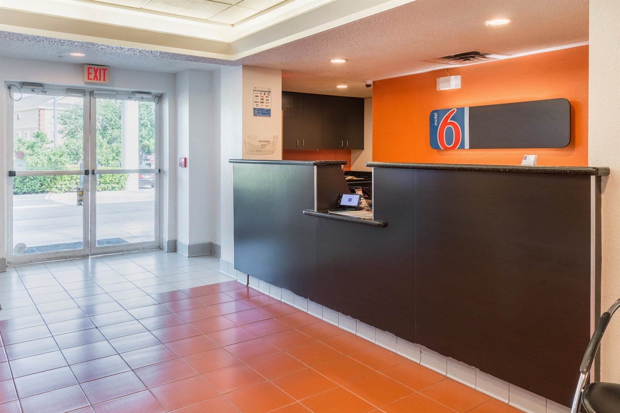 A hotel reception area with a modern design, including a reception desk, a digital screen, and a sign indicating the hotel name 'motel 6'.