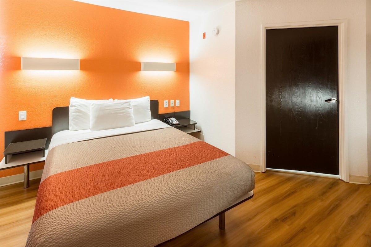 Une chambre d’hôtel avec un lit, des tables de chevet, un téléphone et une porte.