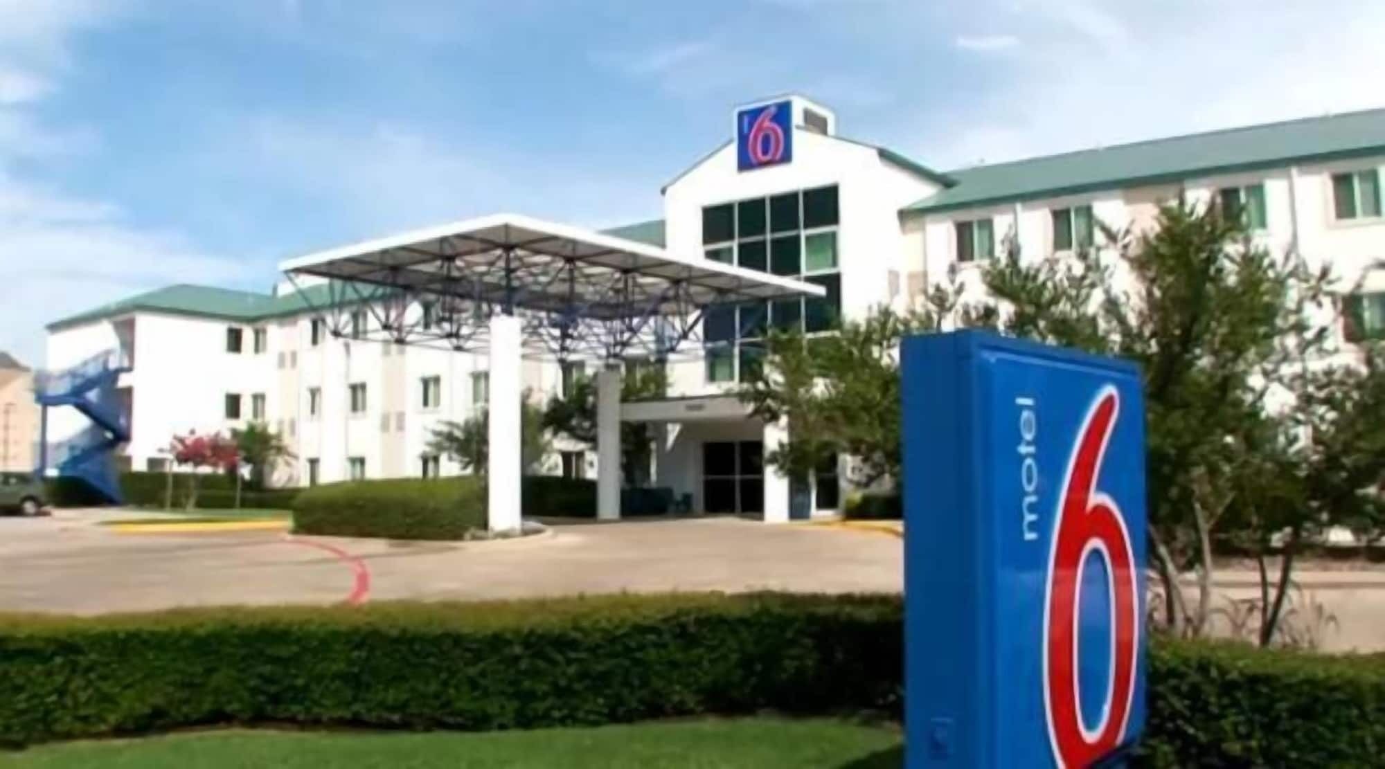 A motel with a large '6' sign, a covered entrance, and a modern building facade.