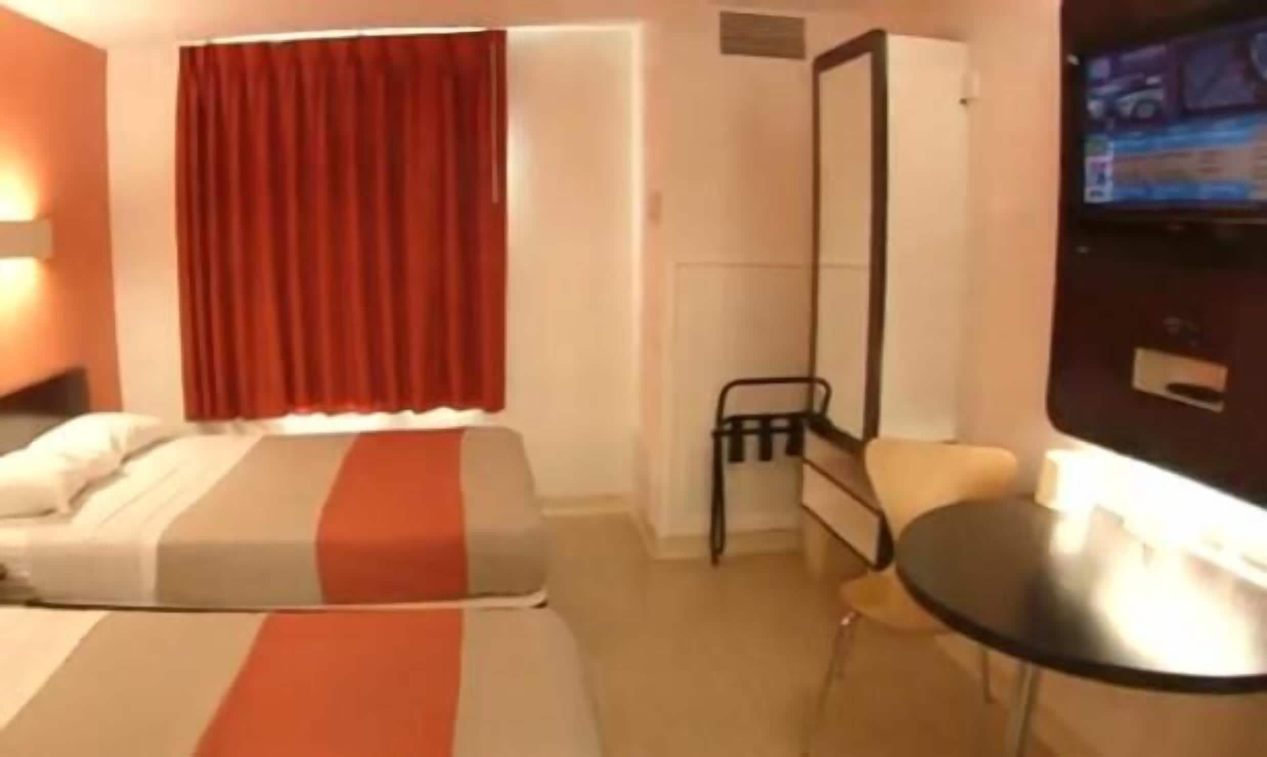 A hotel room with a bed, a chair, a TV, and a wardrobe.