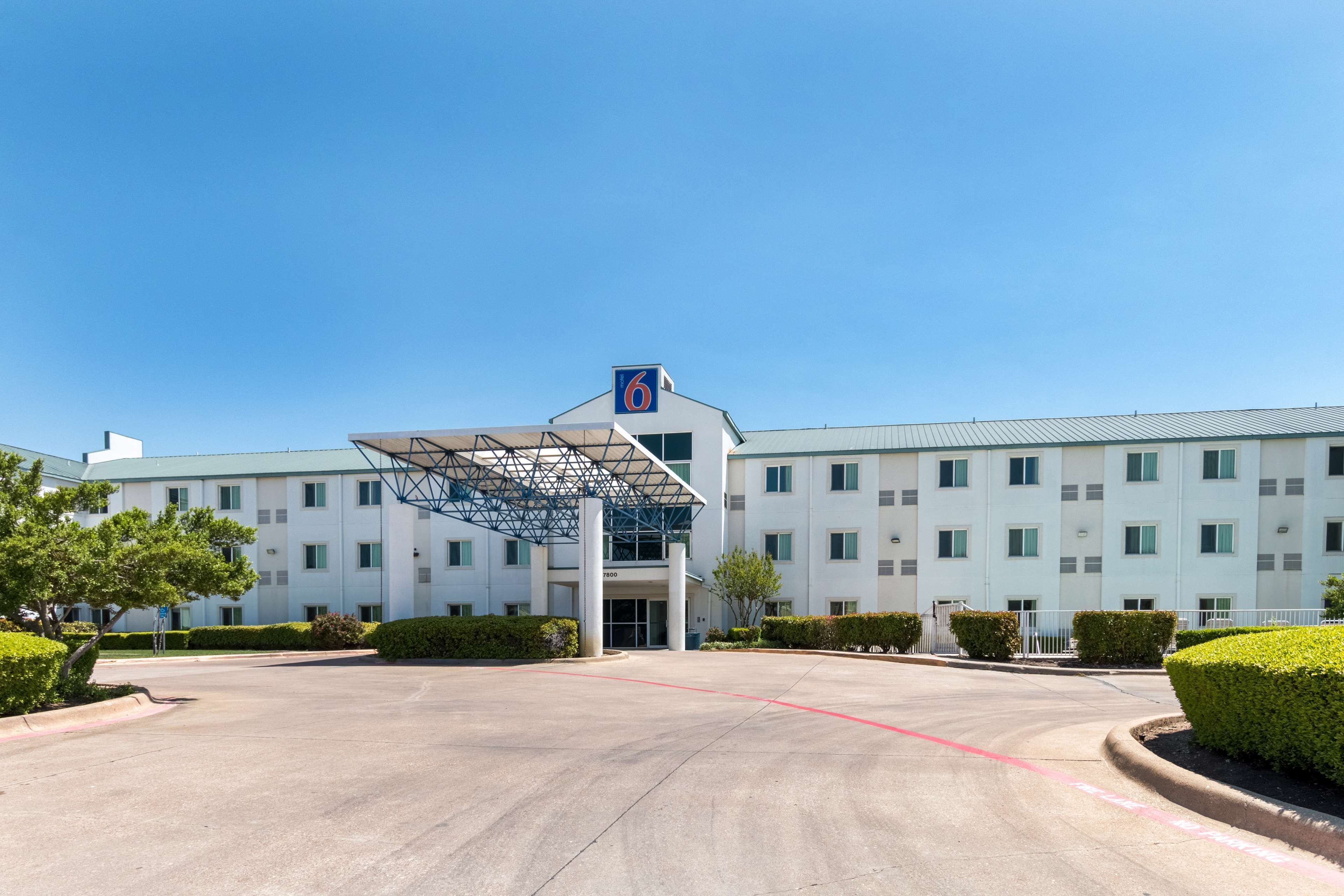 A modern hotel with a large entrance, a covered walkway, and a parking lot.