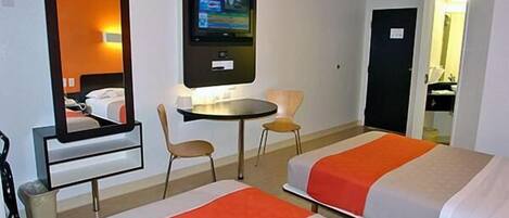 A hotel room with two beds, a TV mounted on the wall, a small round table, and a chair.