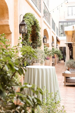 An outdoor courtyard with a round table, potted plants, and a hanging lantern.