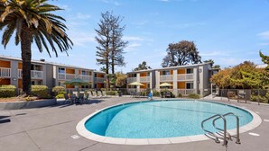 A swimming pool surrounded by a building with balconies and outdoor seating. - Good Nite Inn - Redwood City (Redwood City)