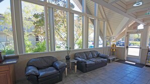 A spacious indoor area with two leather sofas, a small table, and a large window offering a view of the outside. - Good Nite Inn - Redwood City (Redwood City)