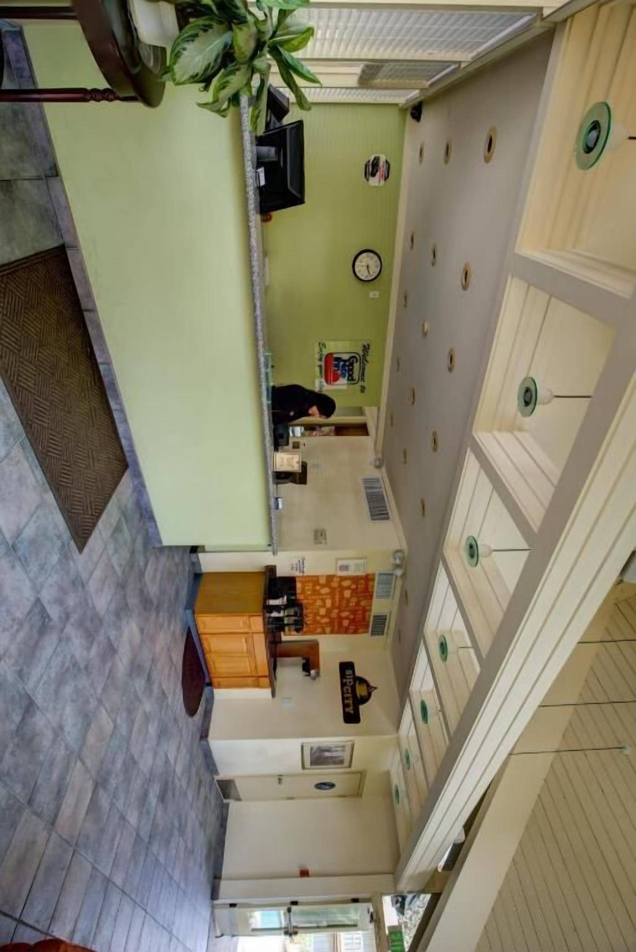 A hotel lobby with a reception desk, a clock, and a plant.