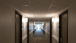 A long, narrow hotel corridor with doors on both sides, a carpeted floor, and overhead lighting. - Good Nite Inn - Redwood City (Redwood City)