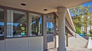 A building entrance with large glass doors, a stone-paved area, and a view of the street and trees. - Good Nite Inn - Redwood City (Redwood City)