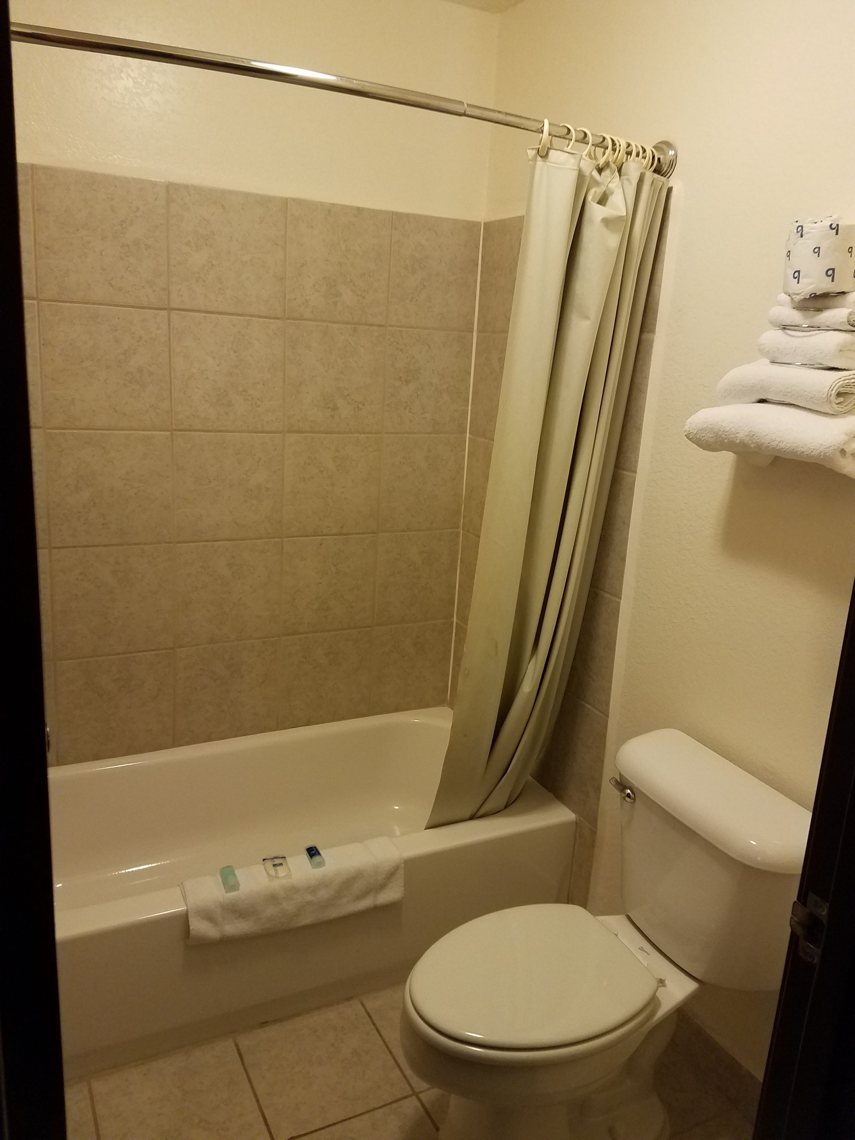 Un baño con bañera, inodoro y toallero con toallas dobladas.