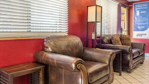 A lobby with leather armchairs, a floor lamp, and a red wall. - Rodeway Inn near Ft Huachuca (Sierra Vista)