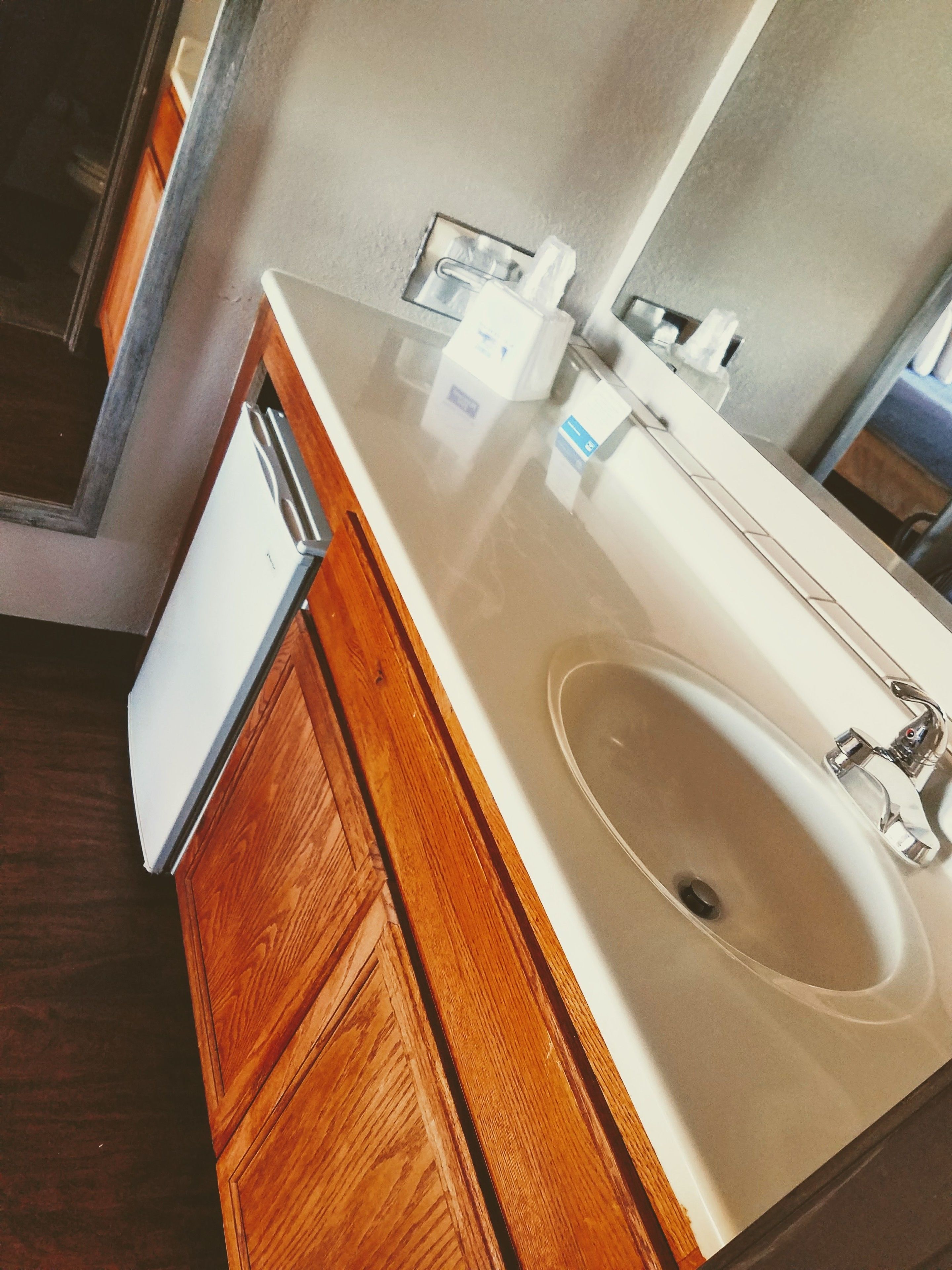 Een badkamer met een witte wastafel, houten kastjes en een spiegel.