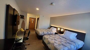 Ett hotellrum med två sängar, ett skrivbord, en stol och en tv.
