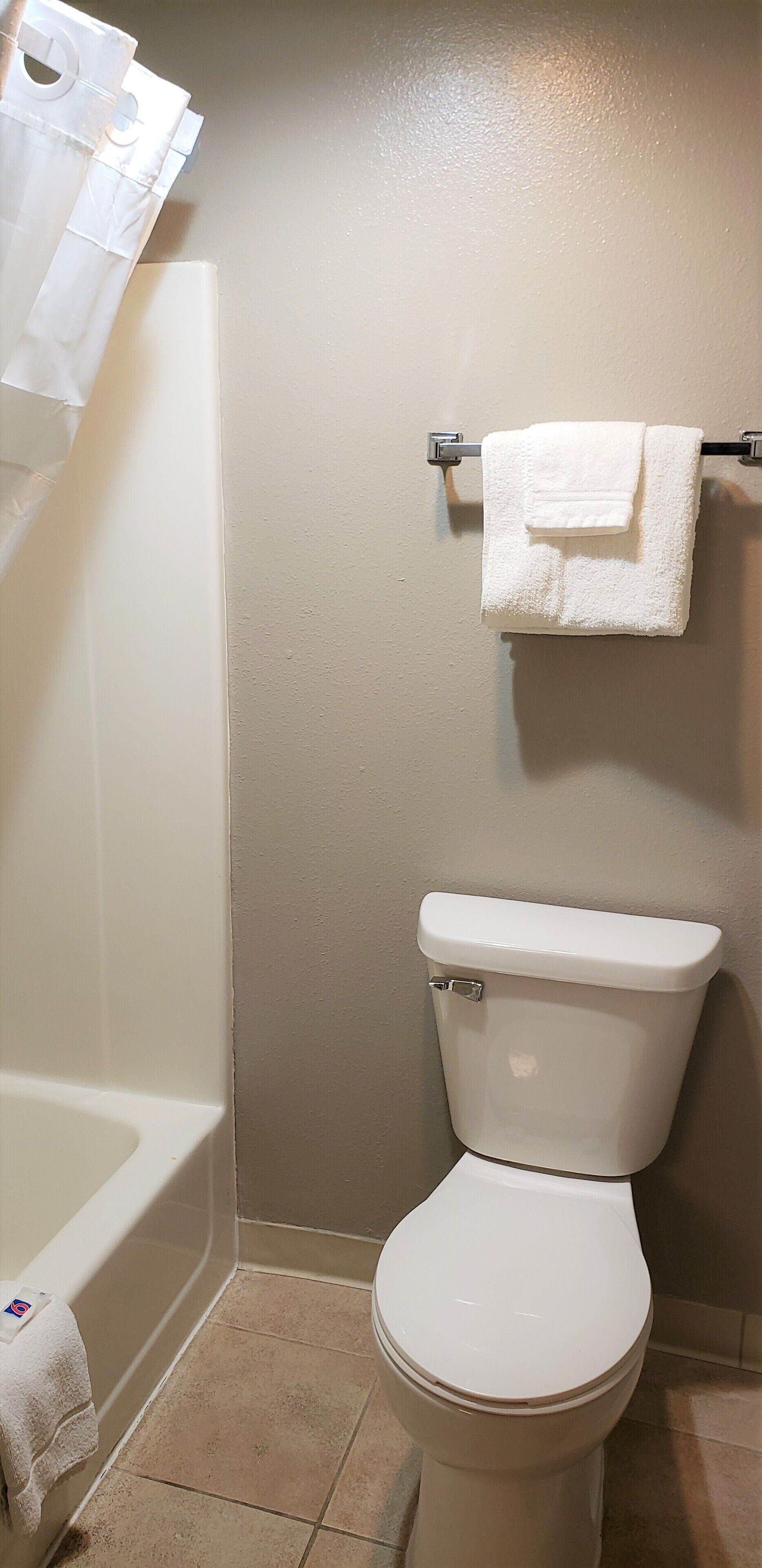A bathroom with a white bathtub, toilet, and a towel rack with a towel.