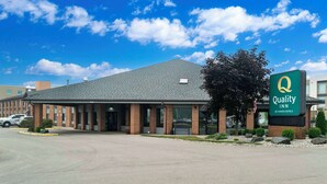 A Quality Inn by Choice Hotels building with a brick facade, large windows, and a parking lot.