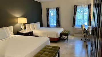 A hotel room with two beds, a desk, a chair, and a bench.