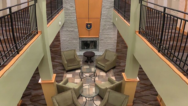 A spacious lobby with a high ceiling, a central fireplace, and multiple seating areas. - Rocklin Park Hotel, Trademark Collection by Wyndham (Rocklin)