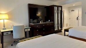 A hotel room with two beds, a desk with a lamp, a dresser, a mirror, and a door. - Rocklin Park Hotel, Trademark Collection by Wyndham (Rocklin)