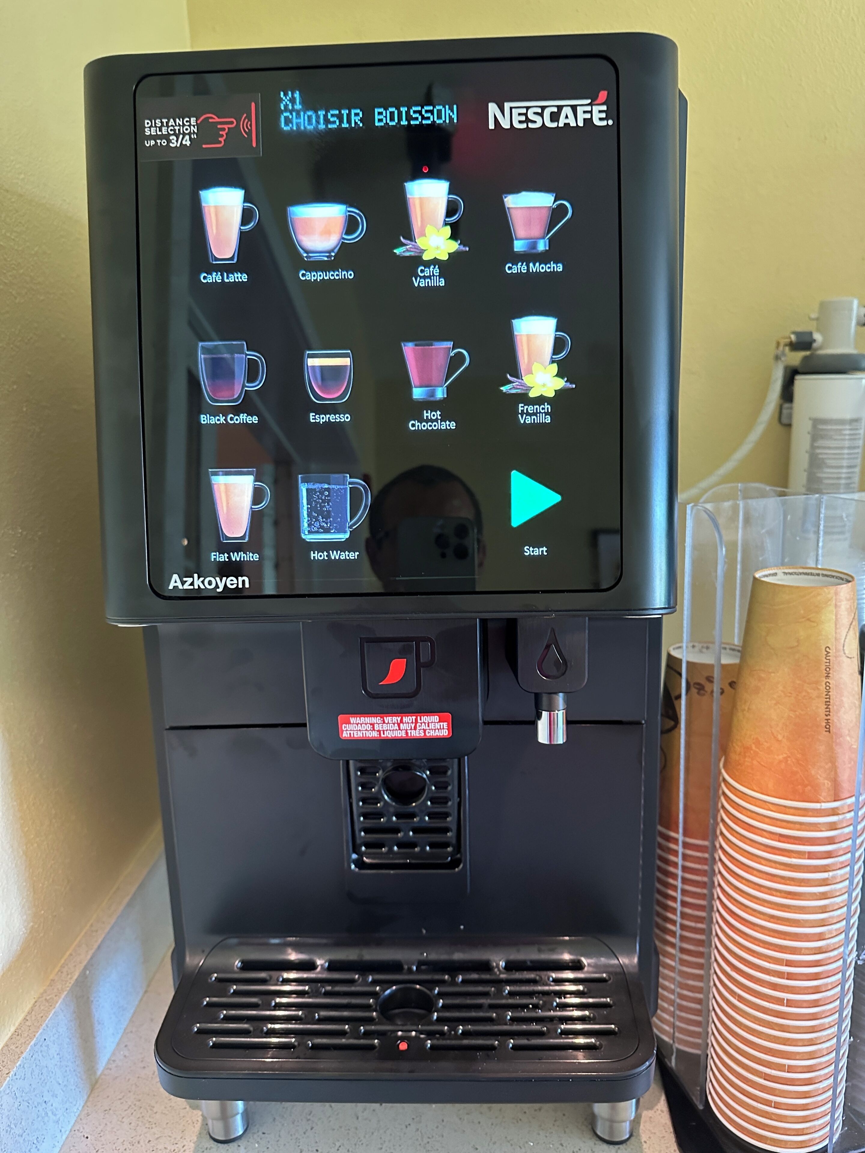 A Nescafé coffee machine with a touchscreen interface displaying various drink options.