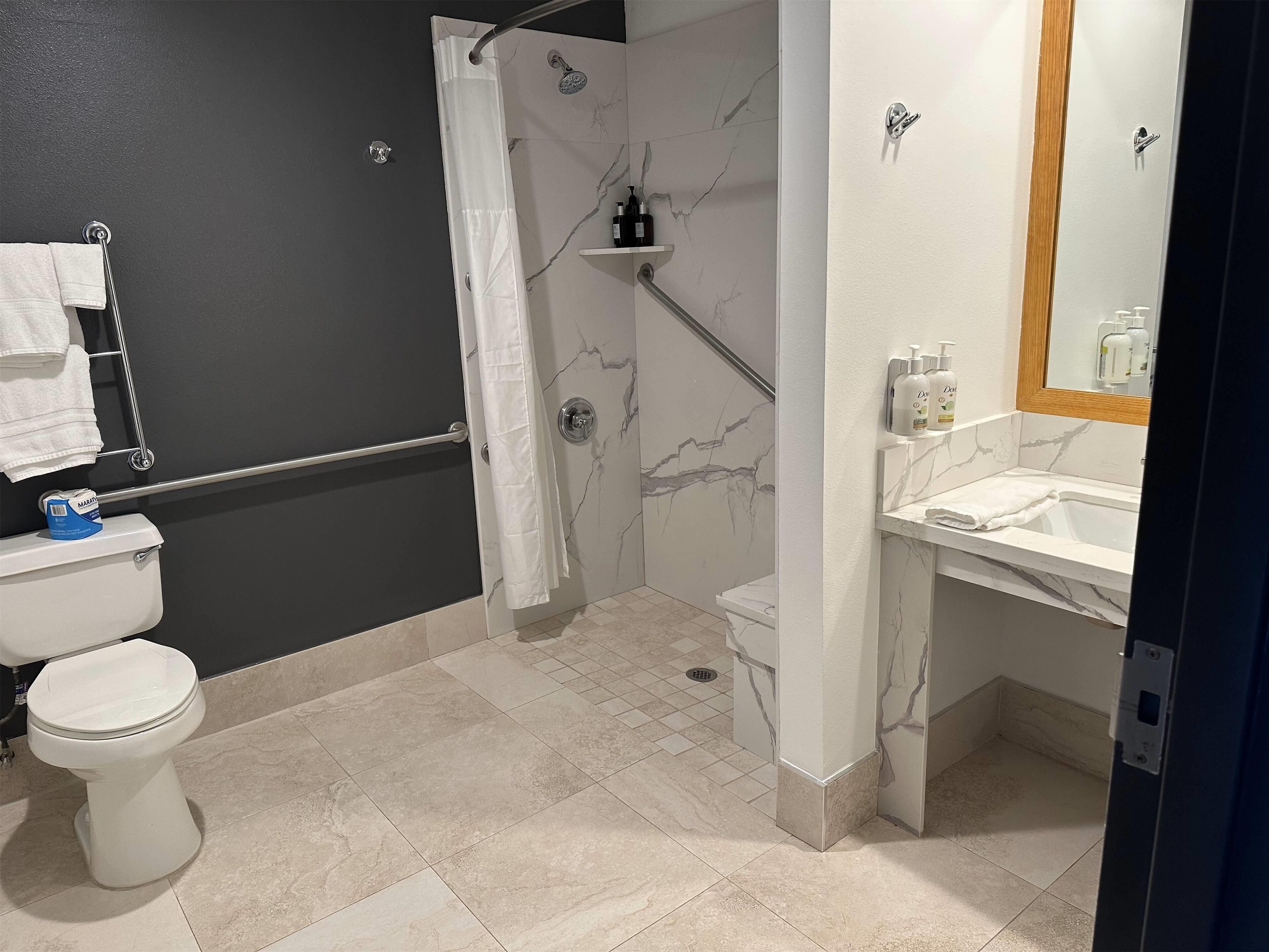 A modern bathroom with a toilet, shower, and sink.