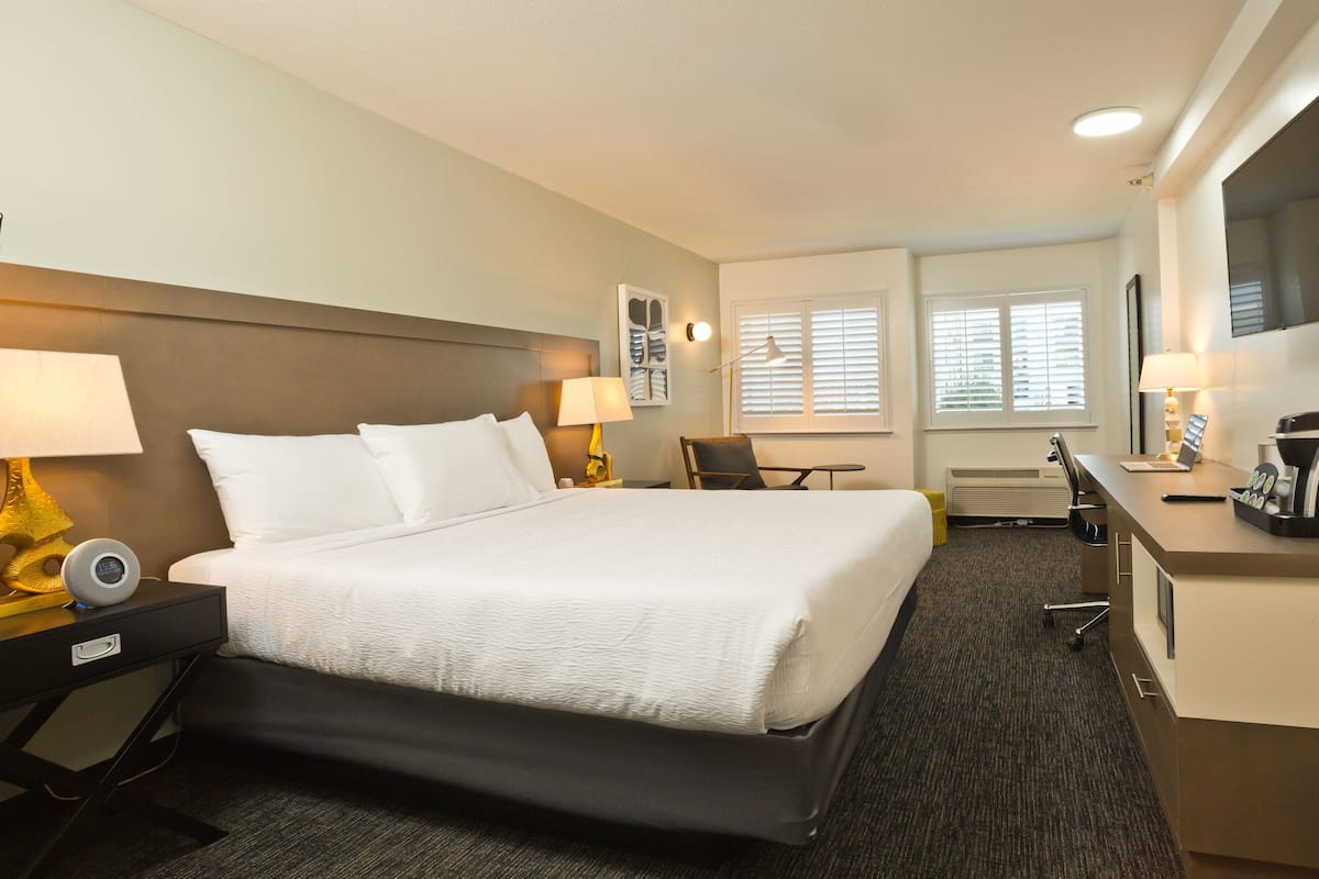 A hotel room with a large bed, bedside tables, a desk, and a chair.