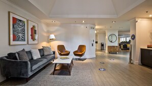 A modern living room with a grey sofa, two armchairs, a coffee table, and artwork on the wall. - The Crestview (Mountain View)