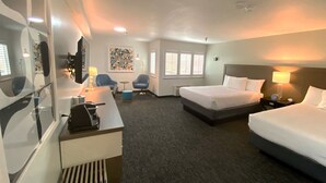 A hotel room with two beds, a desk with a computer, a chair, and a small table. - The Crestview (Mountain View)
