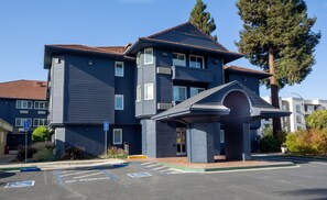 A multi-story building with a dark blue exterior, a red-tiled roof, and a covered entrance.