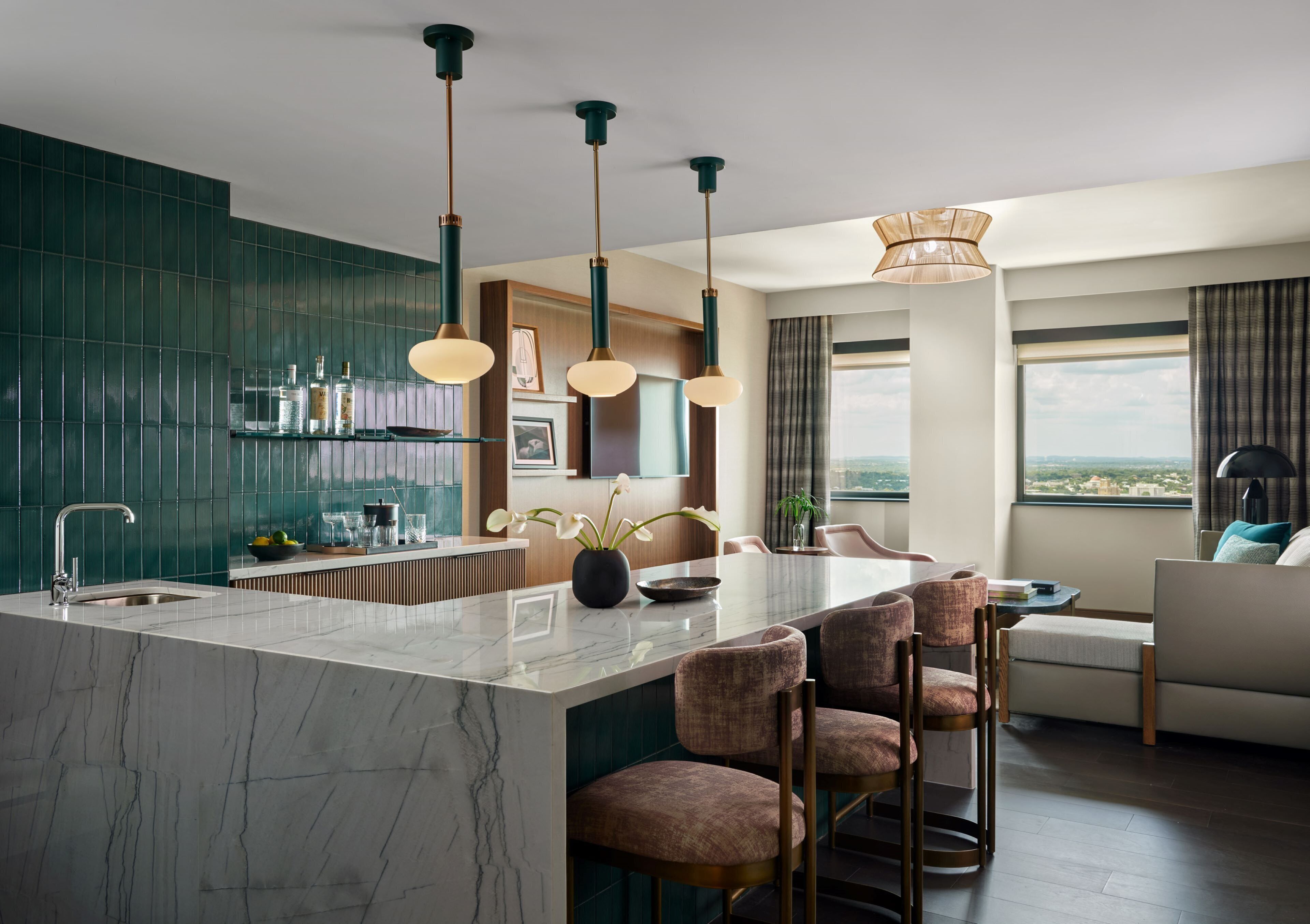 A modern kitchen with a marble island, pendant lights, and a view of the city.