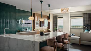 A modern kitchen with a marble island, pendant lights, and a view of the city.