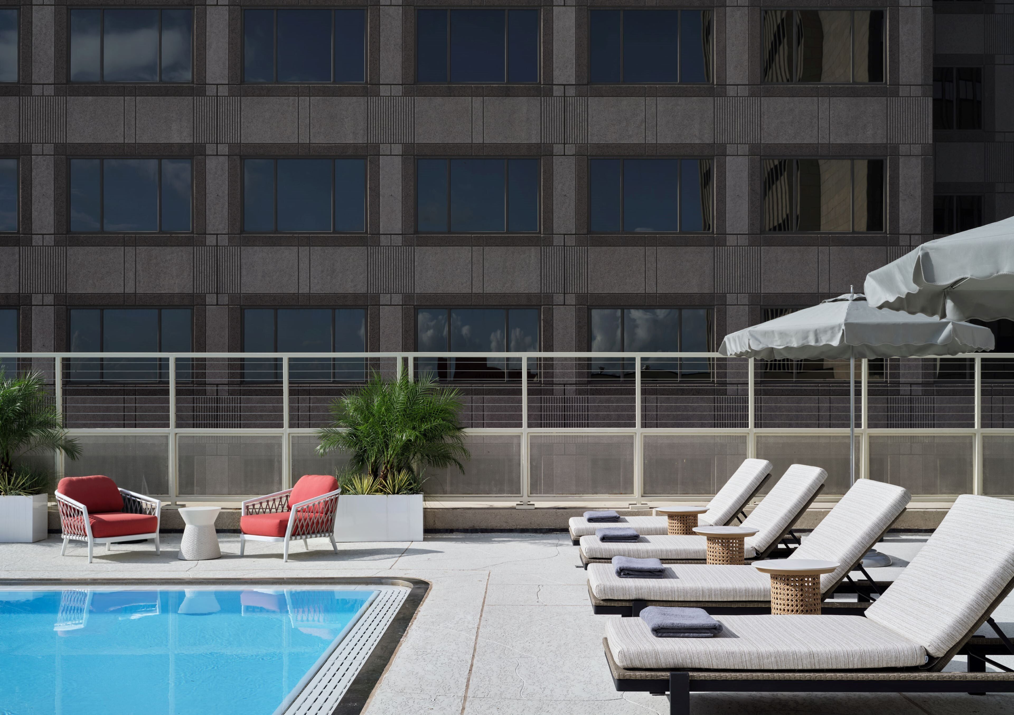 A rooftop pool area with lounge chairs, a small table, and potted plants.