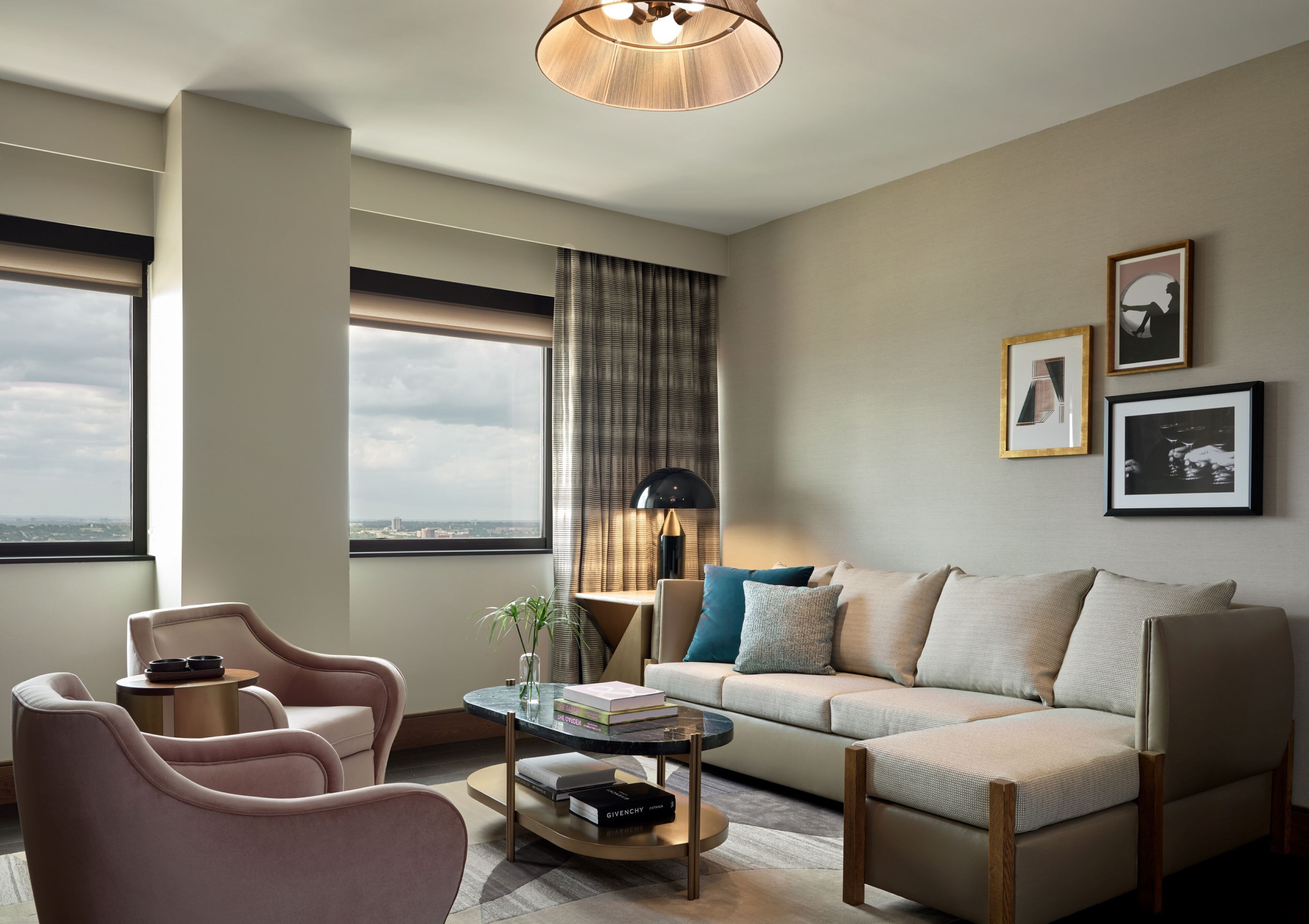 Une chambre d’hôtel moderne, dotée d’un canapé, de fauteuils, d’une table basse et offrant une vue sur la ville.
