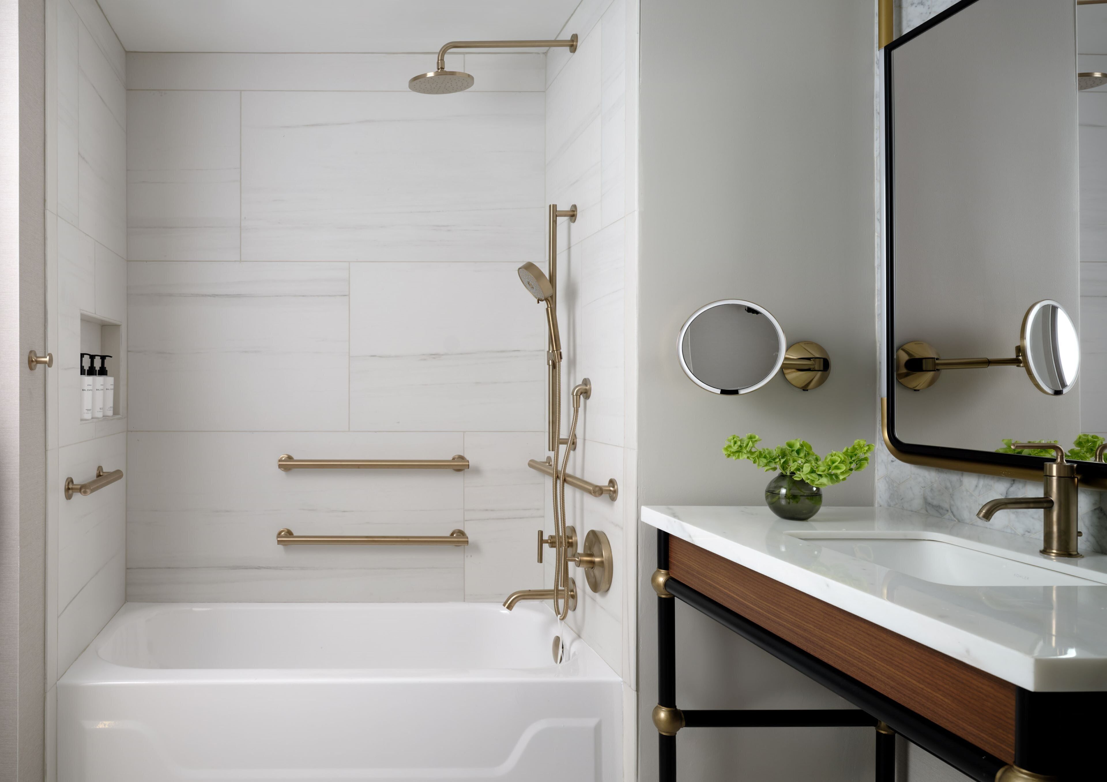 A modern bathroom with a white bathtub, gold fixtures, and a marble countertop.