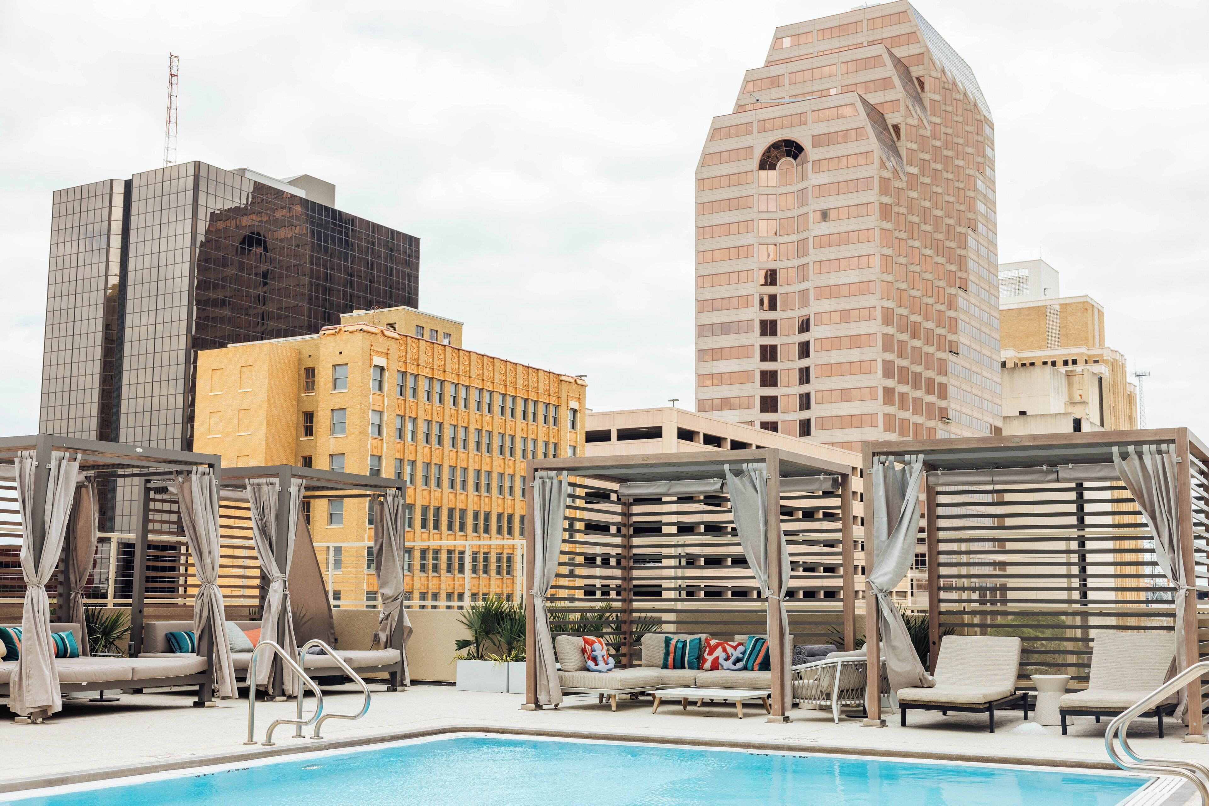 A rooftop pool area with lounge chairs and a view of surrounding high-rise buildings.