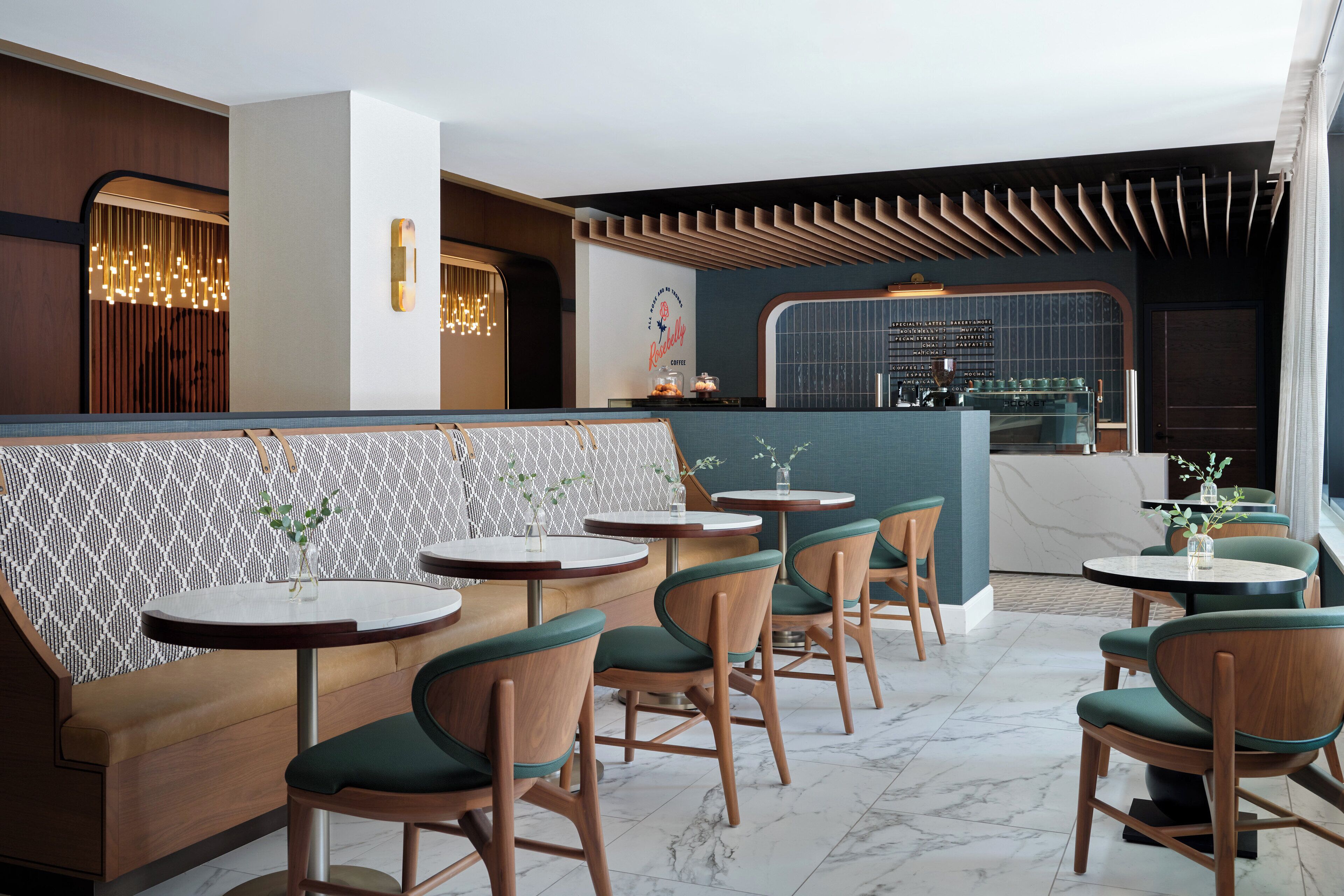 Ein modernes Restaurant mit einer Sitzgruppe an Holzb änken, runden Tischen und einer Bar.