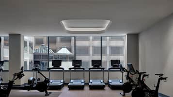 A modern gym with multiple exercise machines, large windows, and a clean, minimalist design.