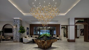 Eine großzügige Lobby mit einem großen Kronleuchter, Marmorböden und modernen Möbeln.