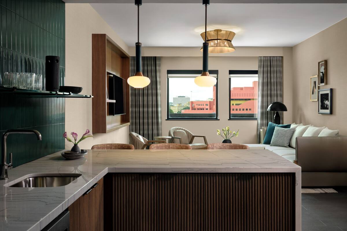 A modern kitchen with a central island, built-in appliances, and a dining area with a sofa and chairs.