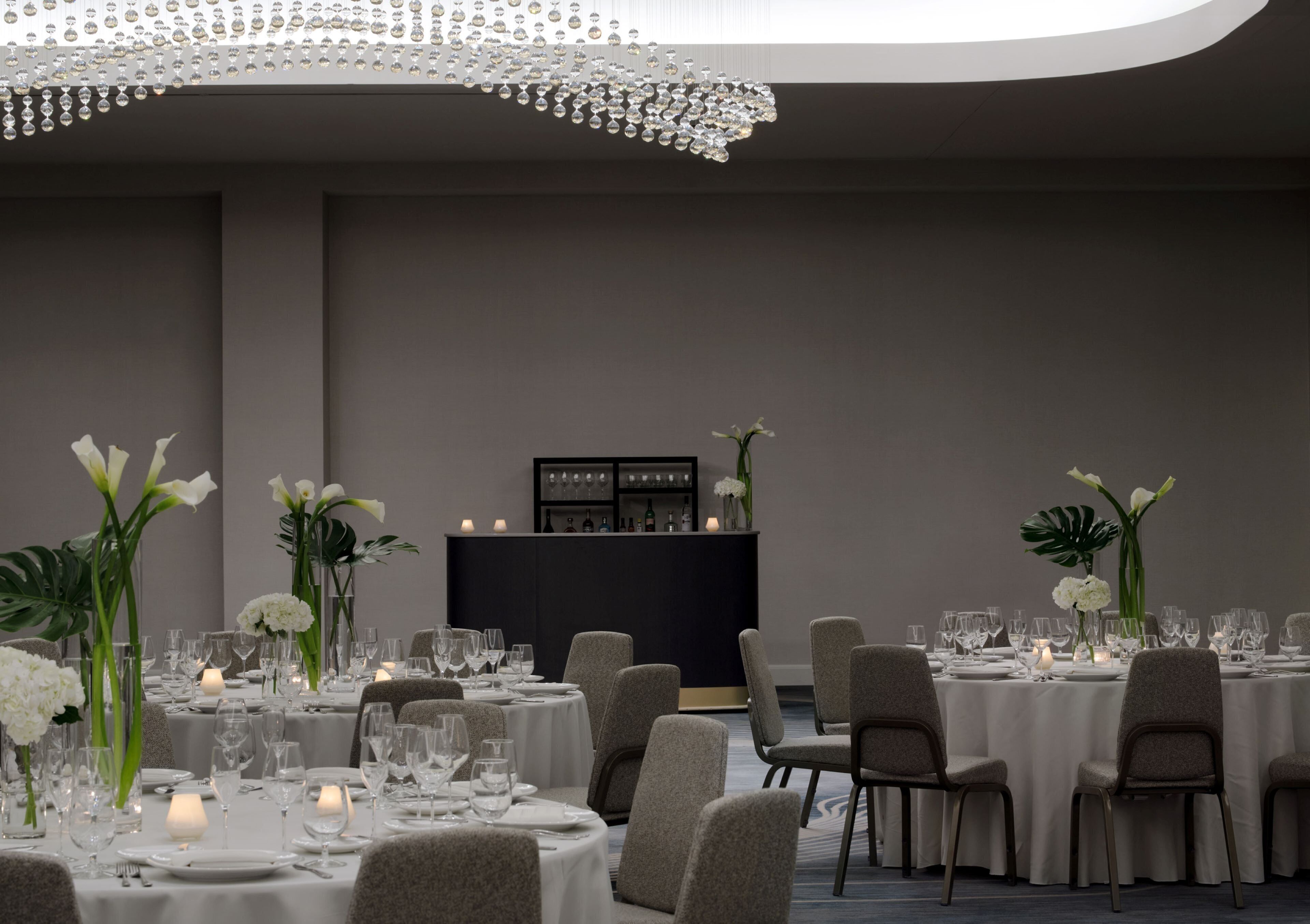 Comedor formal con mesas redondas, sillas y una zona de bar.