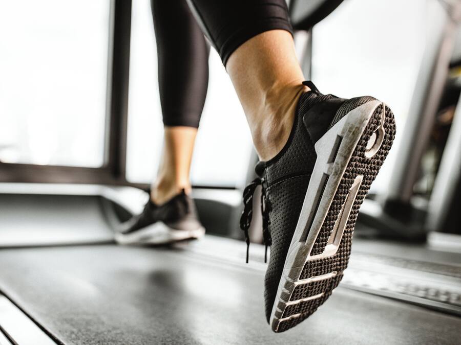 Gros plan sur le pied d’une personne portant une chaussure de course sur un tapis roulant.