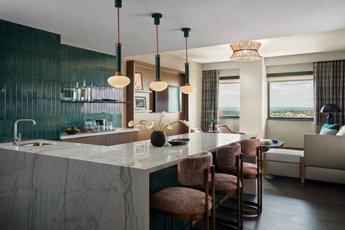 Una cocina moderna con una isla de mármol, luces colgantes y vistas a la ciudad.