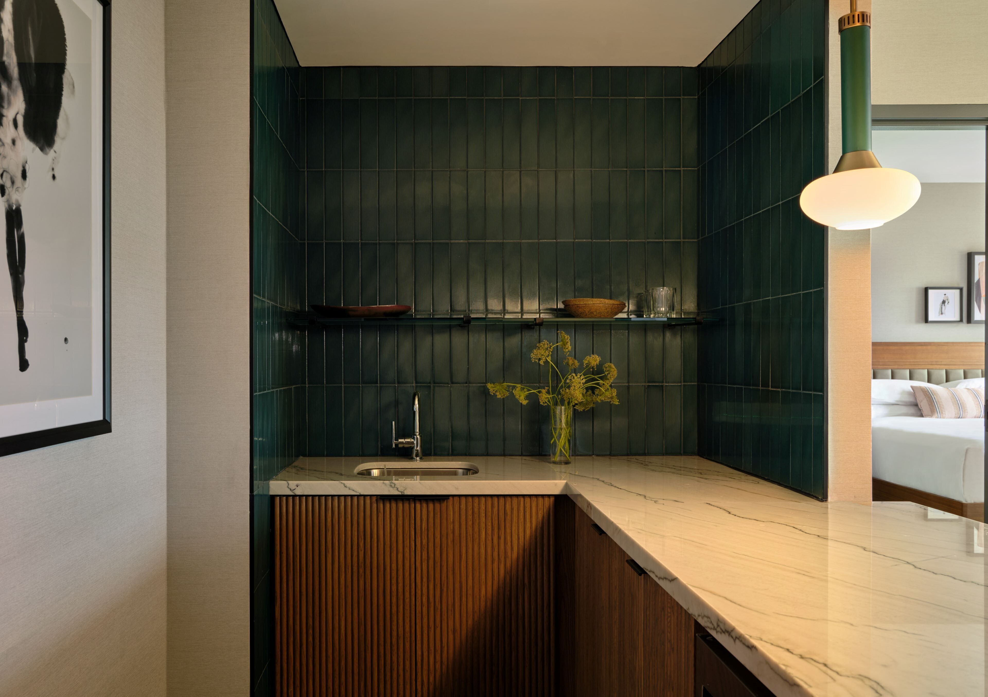 Eine moderne Küche mit Marmorarbeitsplatte, Holzschränken und einer grünen Rückwand.