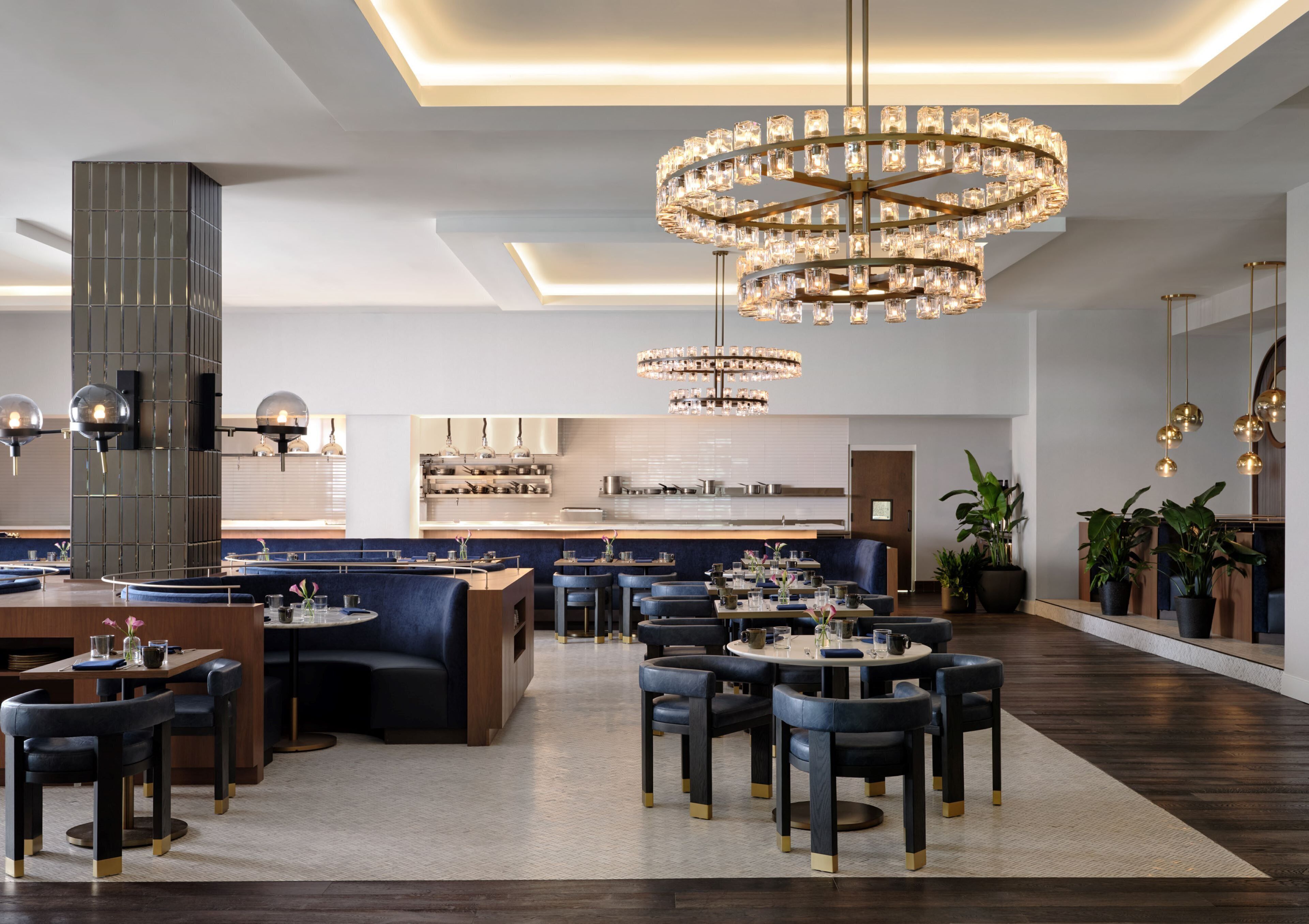 En modern restaurang med ett centralt placerat sittområde, flera bord och en stor kristallkrona.